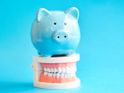 A blue piggy bank sitting on top of a mock jaw model