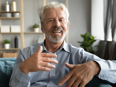An older man sitting on a couch and speaking
