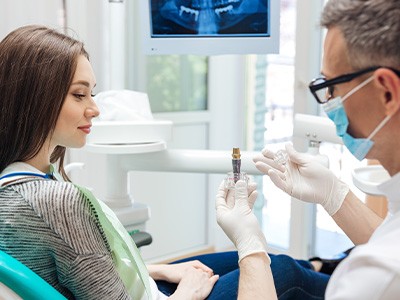 A male dentist showing a dental implant to his female patient