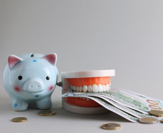 A jaw mockup biting money next to a blue piggy bank